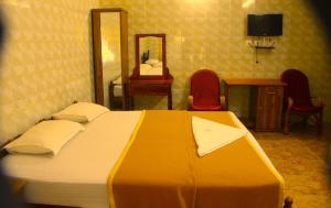 a bedroom with a large bed with a mirror and chairs at Lake Palace Family Resort Kumarakom in Kumarakom