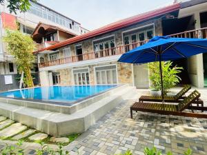 a swimming pool with two chairs and an umbrella at Seals Harbor Hotel in Weligama