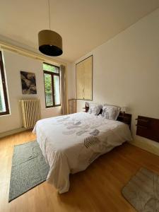 una camera da letto con un letto grande con lenzuola bianche di Villa du parc à La Bourboule a La Bourboule