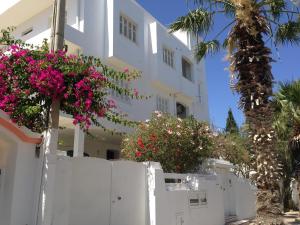 Un bâtiment blanc avec des fleurs devant lui dans l'établissement Appartement Nabeul Plage, à Nabeul