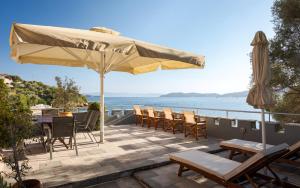 a patio with a table and chairs and an umbrella at Porto Castello Villas in Skiathos