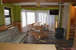 a dining room with a table and chairs and a television at Cabañas Estacion del Lago in Puerto Varas