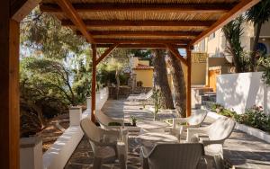 a patio with chairs and tables and a wooden pergola at Porto Castello Villas in Skiathos