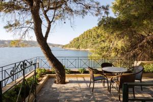 a patio with a table and chairs next to the water at Porto Castello Villas in Skiathos