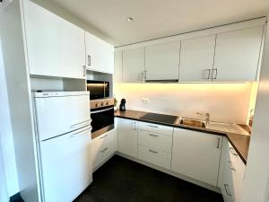 Una cocina con gabinetes blancos y un refrigerador blanco. en K Sunrise, en Ostende
