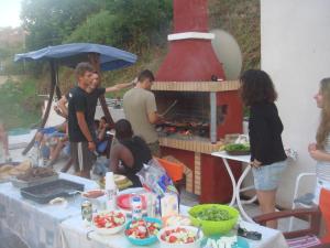a group of people standing around a barbecue grill at Alessandro in Sidari