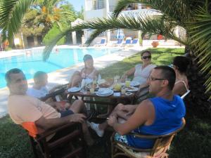 a group of people sitting around a table by a pool at Alessandro in Sidari