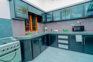 a large kitchen with blue cabinets and a microwave at Pasikuda palm stay in Batticaloa