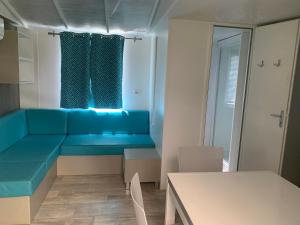 a living room with a blue couch and a table at Mobilhome 6pers Camping le Neptune Argeles sur mer in Argelès-sur-Mer