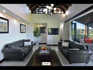 a living room with black leather couches and a table at 13 Yellowwood - with back-up power in Ballito