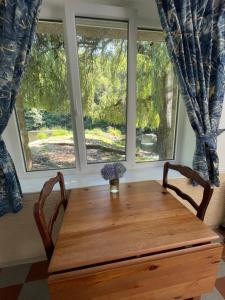 a wooden table in a room with two windows at Le Moulin L'Eveque in Campeaux +38 photos