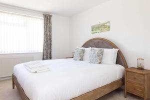 a bedroom with a large bed and a window at 3-Bed Beach Bungalow & Garden 150m to Sea in West Wittering