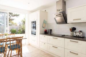 a kitchen with white cabinets and a table and a dining room at 3-Bed Beach Bungalow & Garden 150m to Sea in West Wittering +42 photos
