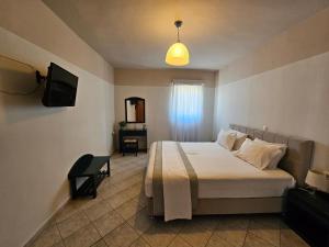 Un dormitorio con una cama y un televisor y una televisión. en Petries Studios, en Agioi Apostoli