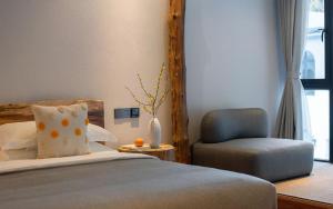 a bedroom with a bed and a chair and a window at Ru Hua's Home LiJiang Artistic Villa in Lijiang