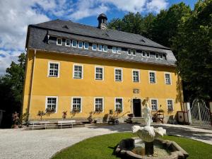 un grand bâtiment jaune avec une statue devant lui dans l'établissement Kavaliershaus neben Schloss Rauenstein, à Rauenstein