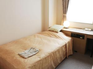 Habitación pequeña con cama, escritorio y ventana. en Hotel Trend Mito, en Mito