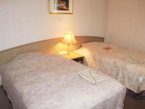 2 camas en una habitación de hotel con una lámpara en una mesa en Hotel Trend Mito, en Mito