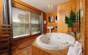 a large white tub in a bathroom with a window at Cozy Bear Camp in Sevierville +28 photos