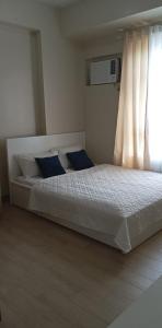 1 dormitorio con cama blanca y almohadas azules en The Verdin Brand-New Unit with Pool, Gym, & High-Speed Wi-fi, en General Trias