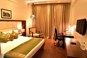 a hotel room with a bed and a desk at Comfort Inn Donil Vadodara in Vadodara