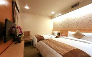 a hotel room with two beds and a tv at Red Cabin Inn in Taipei