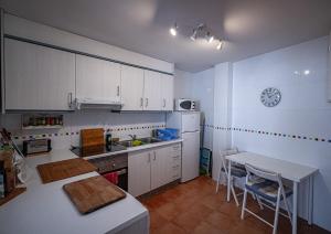 a kitchen with white cabinets and a table and a clock at Piso Playa de Canet in Canet de Berenguer