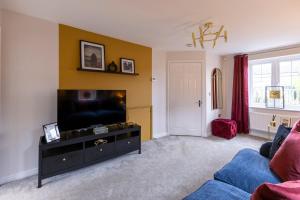 a living room with a tv and a blue couch at Stunning and Bright 3-bed Home in Nottingham by Renzo, Free Parking, Next to M1! in Pinxton