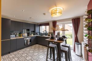 a kitchen with black cabinets and a table with stools at Stunning and Bright 3-bed Home in Nottingham by Renzo, Free Parking, Next to M1! in Pinxton