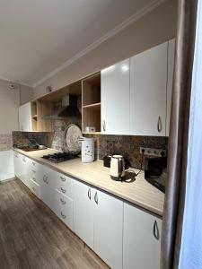 a kitchen with white cabinets and a counter top at Del Hostel in Almaty +12 photos