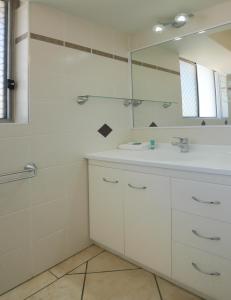 a white bathroom with a sink and a mirror at Merrima Court Holidays in Caloundra