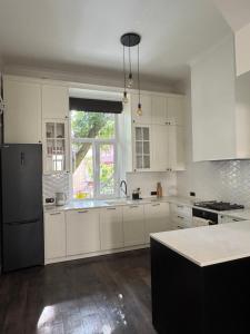 Una cocina con gabinetes blancos y un refrigerador negro. en Kobylianska Apartments, en Chernivtsi