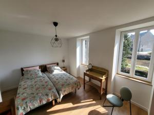 a bedroom with a bed and a table and two windows at "La maison d'Octavie" in Rieupeyroux