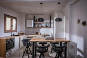 Una cocina con una mesa de madera y algunos taburetes negros. en Cosmopolis Crete Suites, en Hersonissos