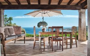 a patio with a table and chairs and an umbrella at Sea View Grande Pevero 5 in Porto Cervo