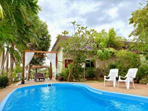 奈扬海滩运河度假村的房子前面有游泳池,有两把椅子和一栋房子