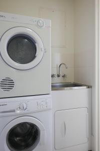 a white microwave sitting next to a white sink at Merrima Court Holidays in Caloundra