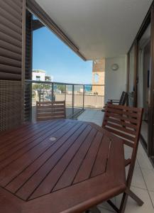 a deck with a wooden table and chairs on a balcony at Merrima Court Holidays in Caloundra