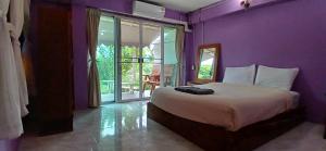 una camera con un letto con una parete viola di ปอ อา ยอ รีสอร์ท a Pai