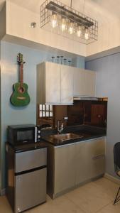 a kitchen with a sink and a guitar on the wall at Studio Premier Suite Makatii by Christine Suites PH in Manila