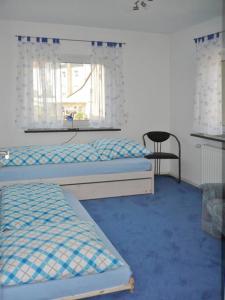 a bedroom with two beds and a window and a chair at Ferienwohnung beim Steinmetzmeister im Quarzwerk in Lautertal