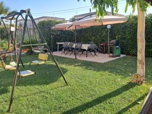 a swing set with an umbrella and chairs in a yard at B&B Villa Rosa in SantʼAntonio Abate