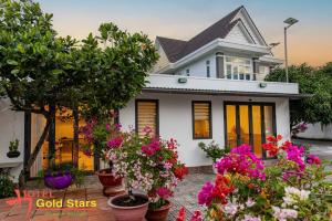a white house with lots of potted plants at gold star homestay in Long Hai