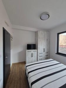 a white bedroom with a bed and a window at Villa Obednikovski in Ljubojno