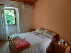 a bedroom with a bed with white sheets and a window at Ferienhaus in Frontone in Frontone