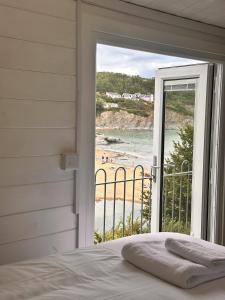 a bedroom with a bed and a view of a beach at Cwtch Glanmordy by Aberporth Beach Holidays in Aberporth