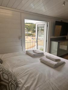 a bed with two towels on it with a view of a beach at Cwtch Glanmordy by Aberporth Beach Holidays in Aberporth