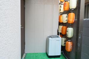 a wall with a trash can and lanterns on it at 四季安々 in Tokyo
