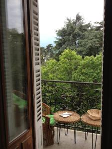 a balcony with tables and chairs and a view of trees at Chez Anna in Aix-les-Bains