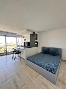 a bedroom with a bed and a kitchen and a table at Beau studio dans résidence avec piscine et vue sur la ville - 5min des plages in Mandelieu-La Napoule